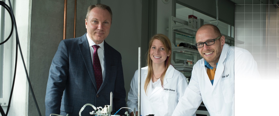 2 students and a professor posing in a lab
