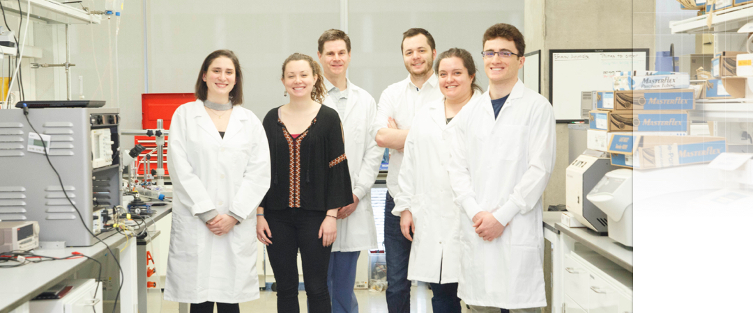 group of students and professor posing in their research lab